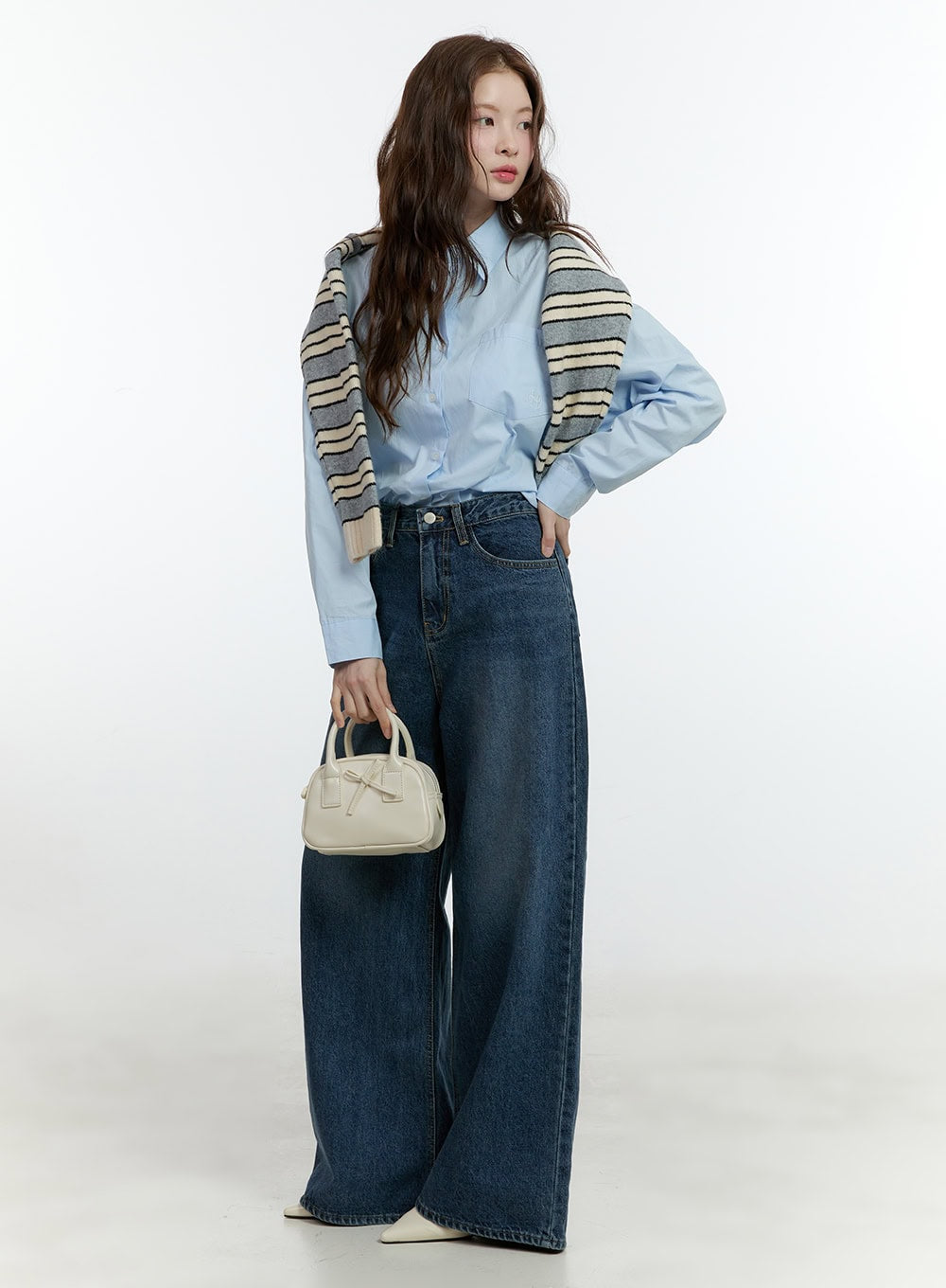 Klaudia Wide-Leg Jeans CF503 in blue, front three-quarter shot on model, wide-fit washed denim, styled with blue shirt and striped knit draped over shoulders, cream mini bag.