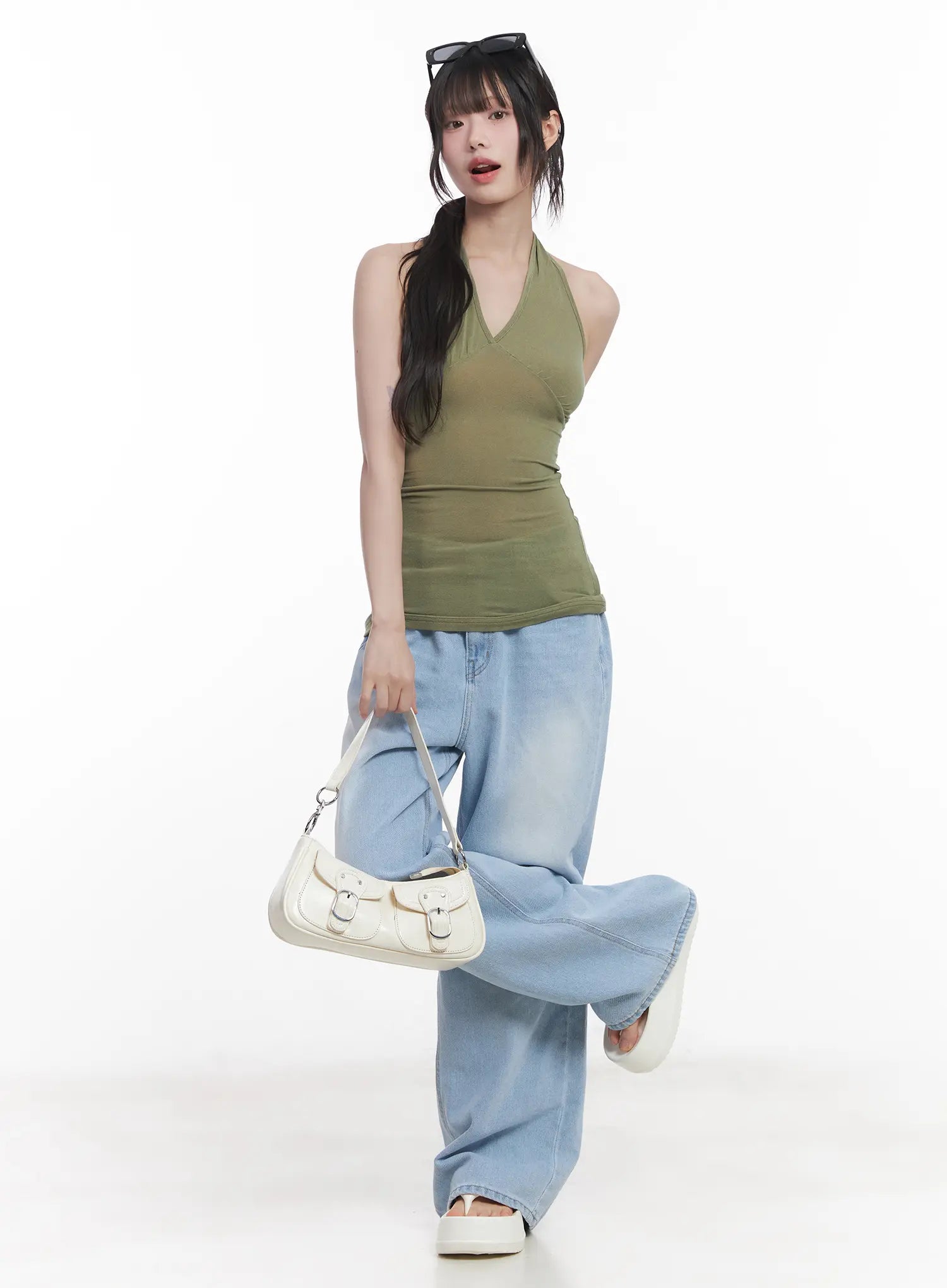Haerin Washed Wide-Leg Jeans CU519 in light blue, full-body dynamic front shot on model, wide-leg washed denim with street-style pose, styled with olive halter top and white shoulder bag.