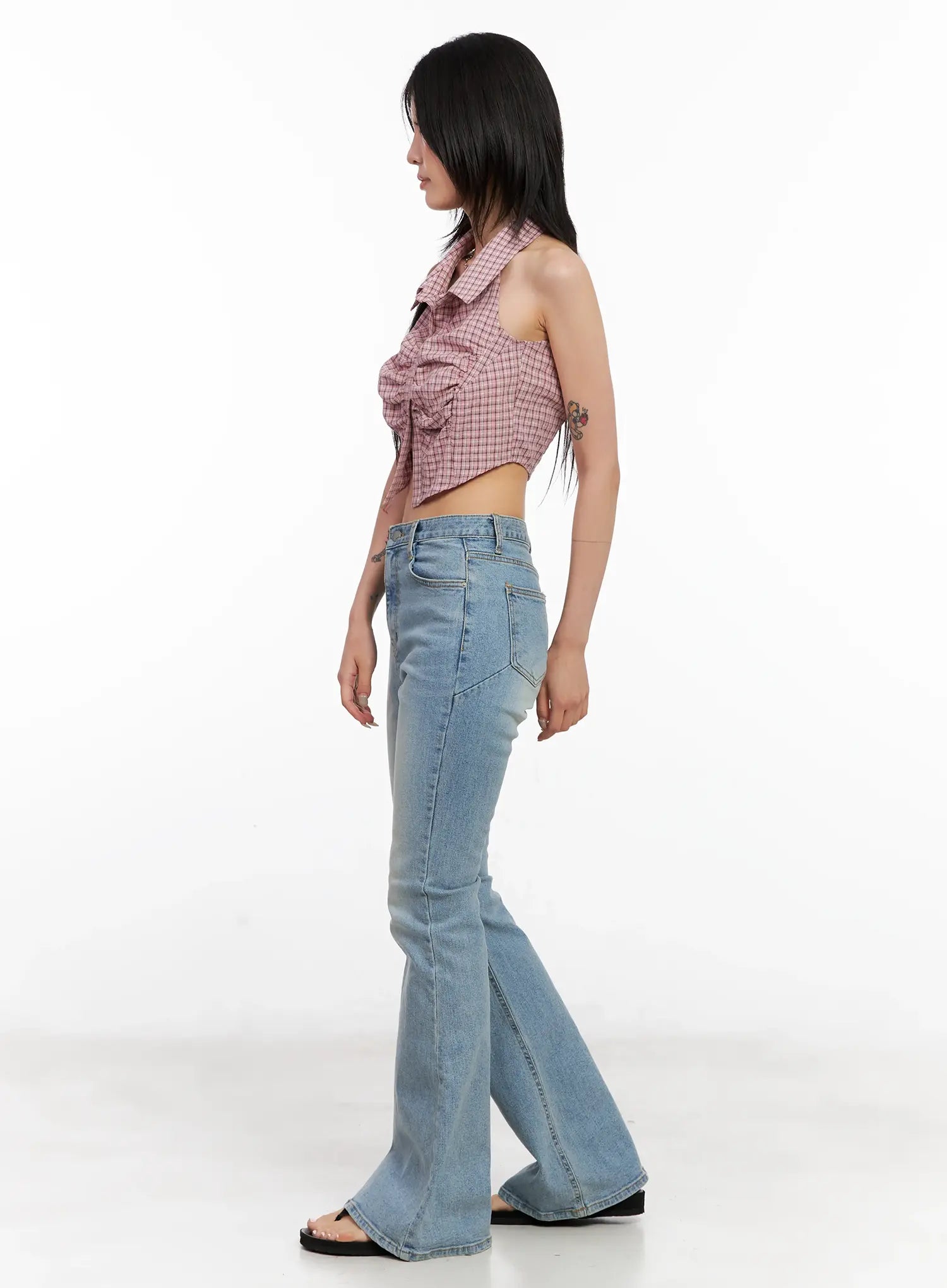 Byeol Washed Flare Denim Jeans CL525 in light blue, side profile on model showing back pocket placement and flared hem, styled with pink plaid halter crop top.