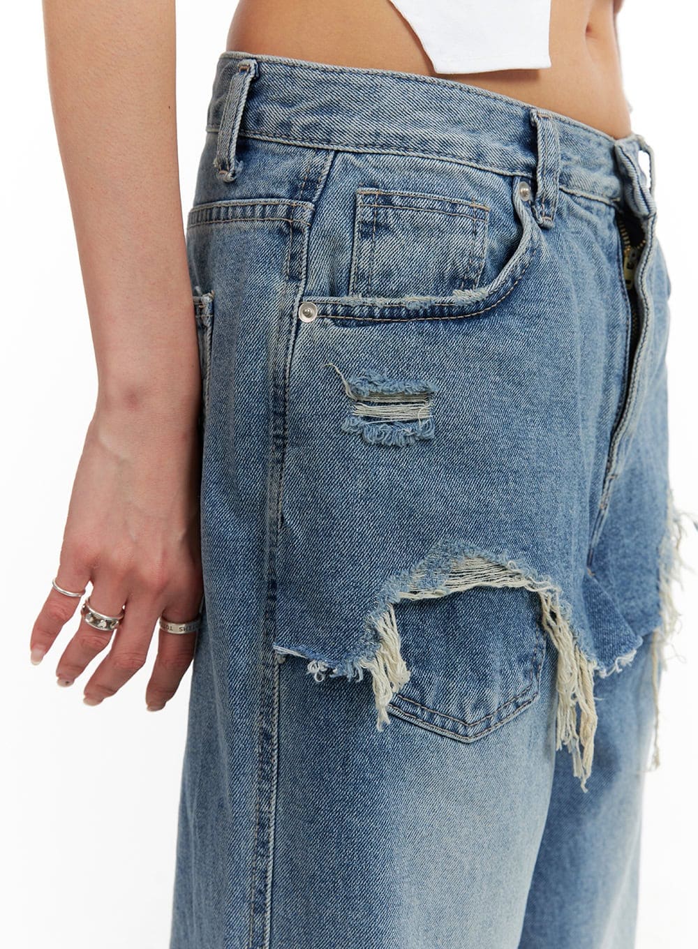 Layered Wide Leg Jeans CA430 in Blue, side close-up detail on model, showing destroyed ripped holes and frayed edges on thigh panel beneath layered skirt overlay, washed cotton denim texture.