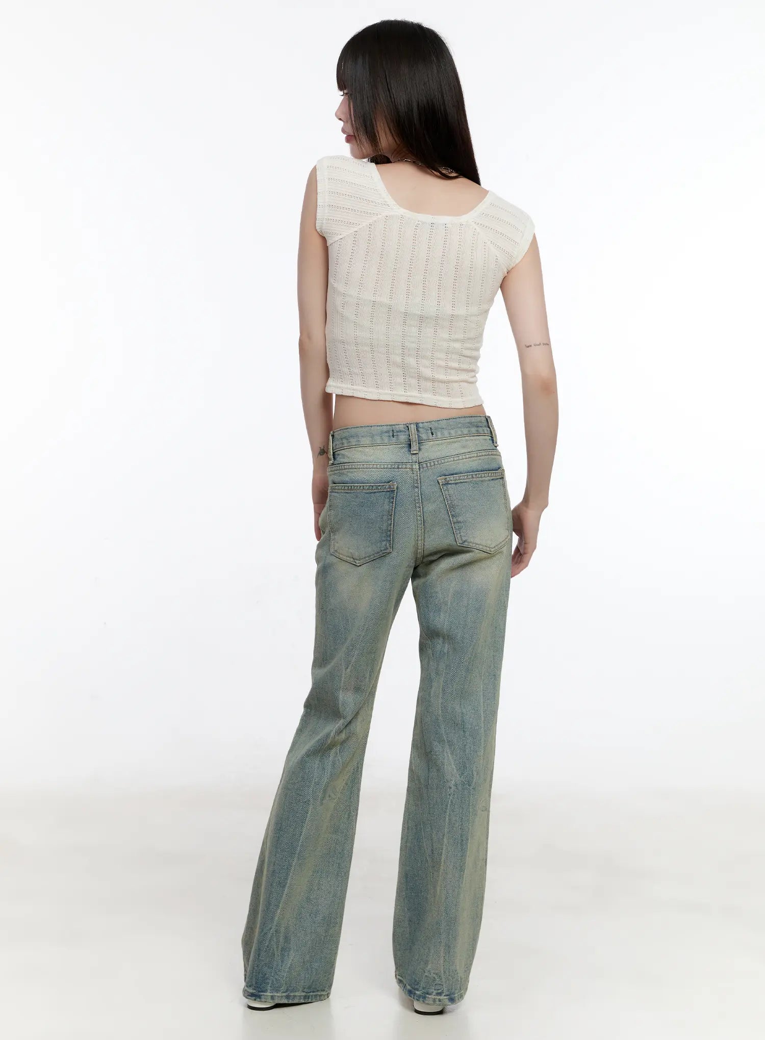Roa Vintage Blue Flared Denim Jeans CL504 in blue, full-body back shot on model, washed bootcut silhouette with back pockets visible, paired with cream pointelle knit crop top, white flats.