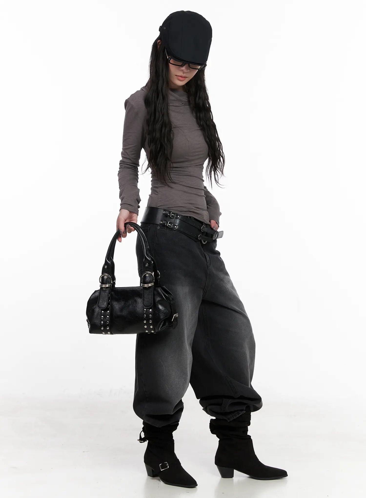 Yuji Dark-Washed Baggy Jeans CN513 in black, full-body front editorial shot on model, belted with double-buckle leather belt, styled with gray turtleneck, black studded bag, cap, and buckle boots.
