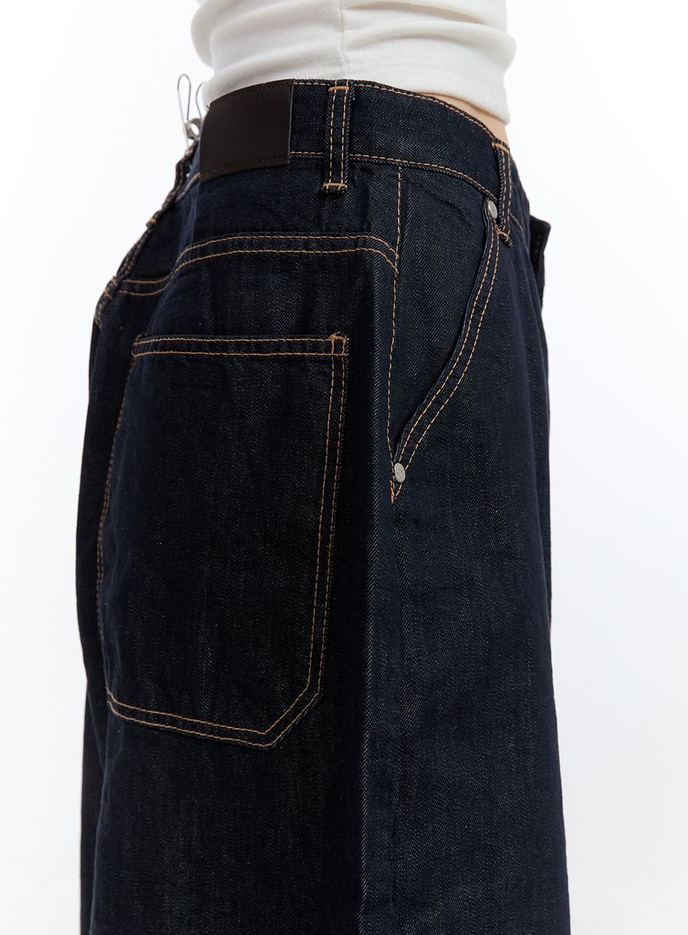 Dora Stitched Baggy Jorts CG413 in dark blue, macro detail close-up of back pocket and waistband, showcasing contrast golden topstitching, rivet hardware, and dark indigo denim texture.