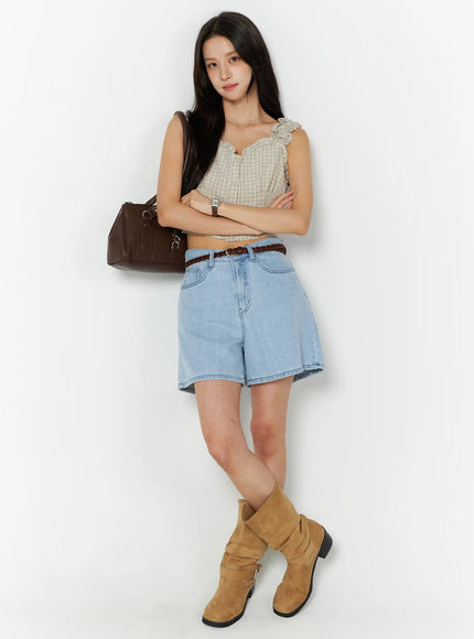 Plaid Ruffle Sleeveless Top CU522 in beige, full-body front view on model with arms crossed, cropped plaid top and ruffle straps, styled with denim shorts, braided belt, and tan boots.