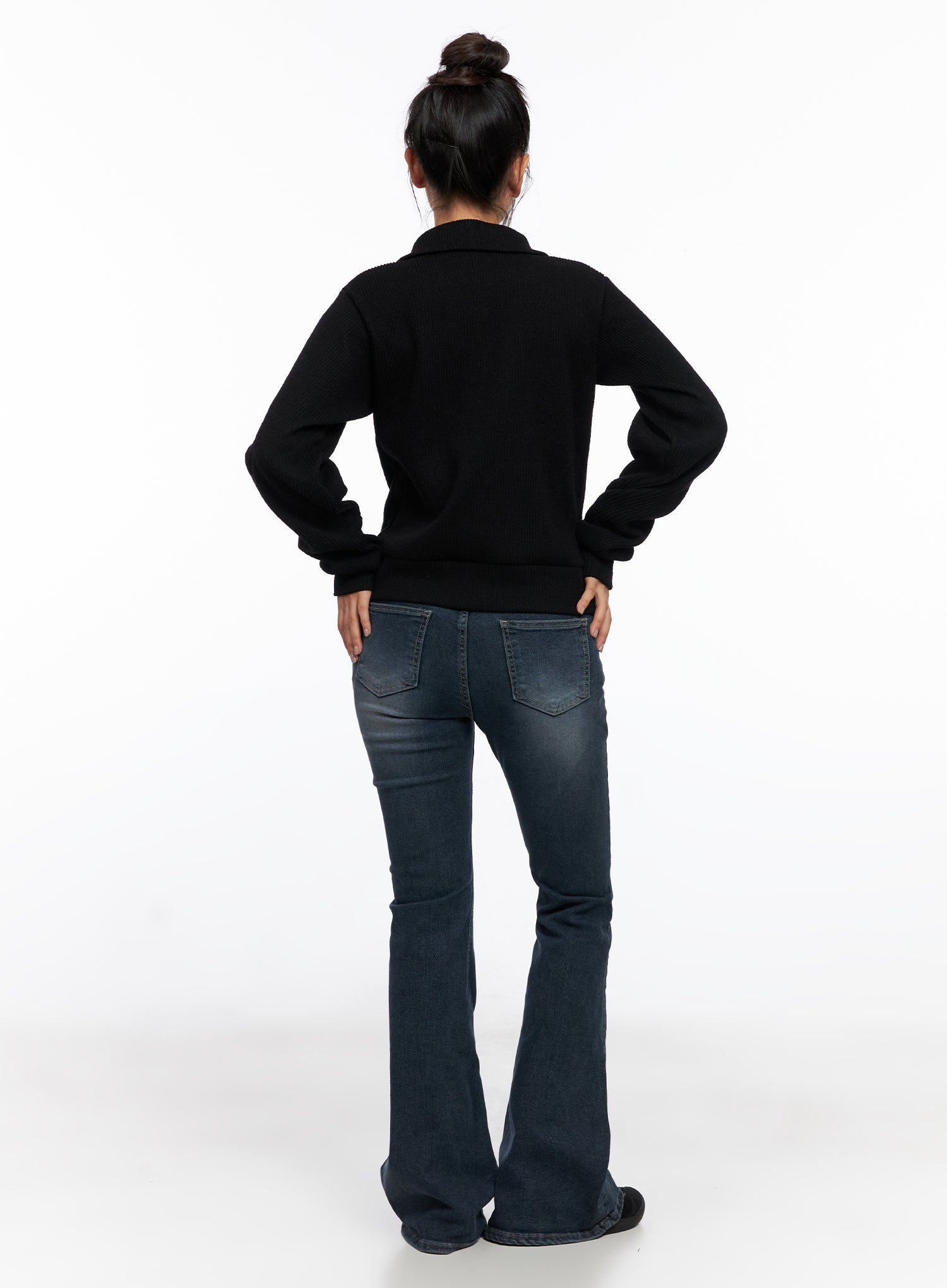 Melina Hip-Pad Low-Rise Flare Jeans CO514 in dark blue, full-body back on model styled with black zip jacket, hands on hips, back pockets and flare silhouette clearly visible.