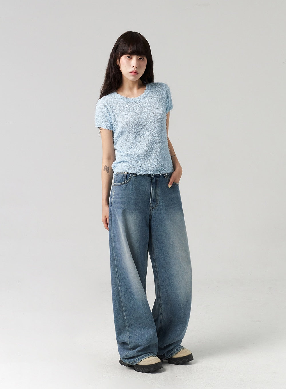 Baggy Jeans CL313 in washed blue, full-length slight-angle front view on model, one hand in pocket, extra-wide leg denim with sun-bleached wash, worn with bouclé tee.