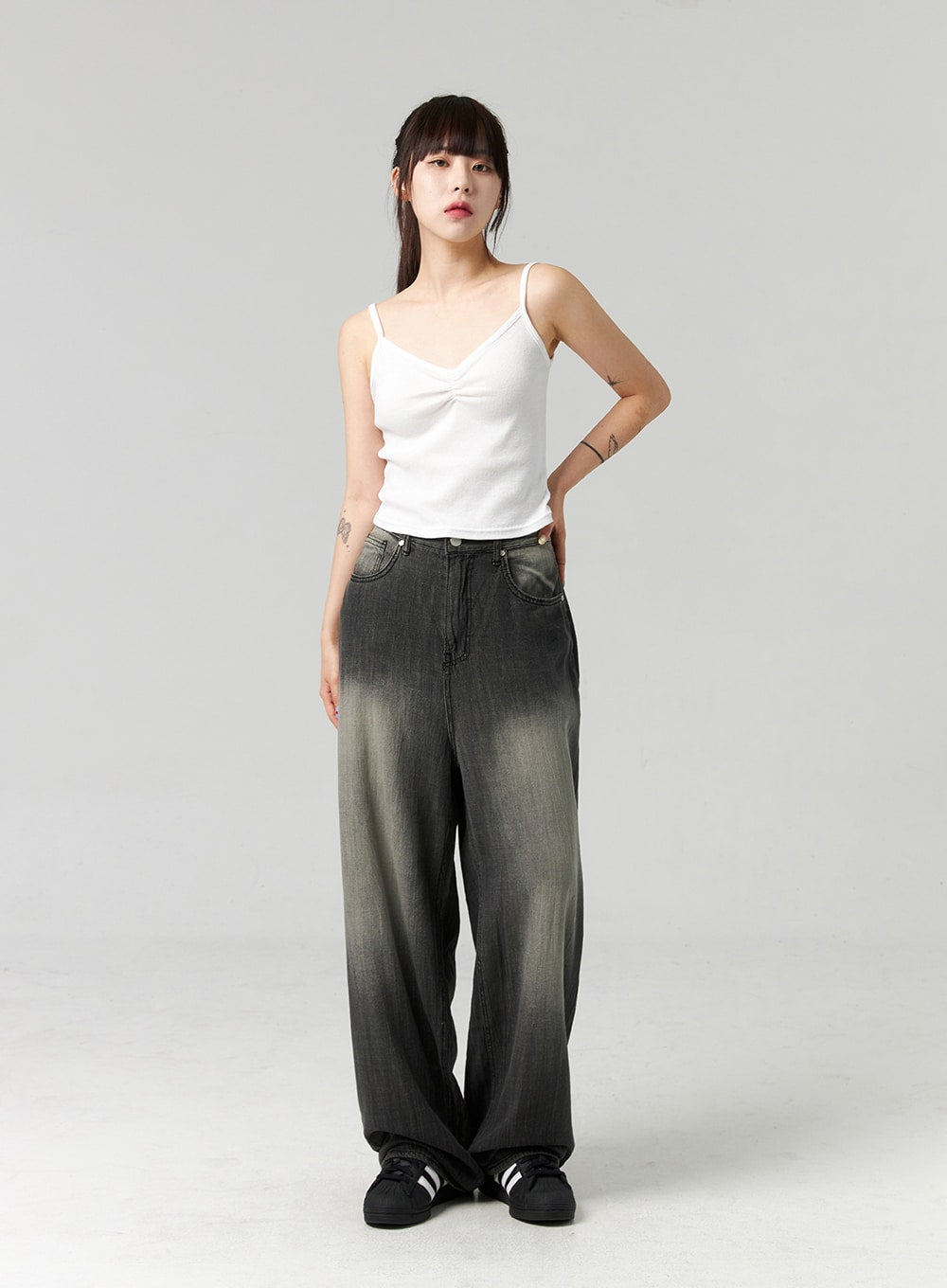 Baggy Jeans CL321 in washed dark grey, full-body three-quarter front view on model, wide-fit gradient cotton denim with faded finish, hand on hip, worn with white spaghetti-strap top.