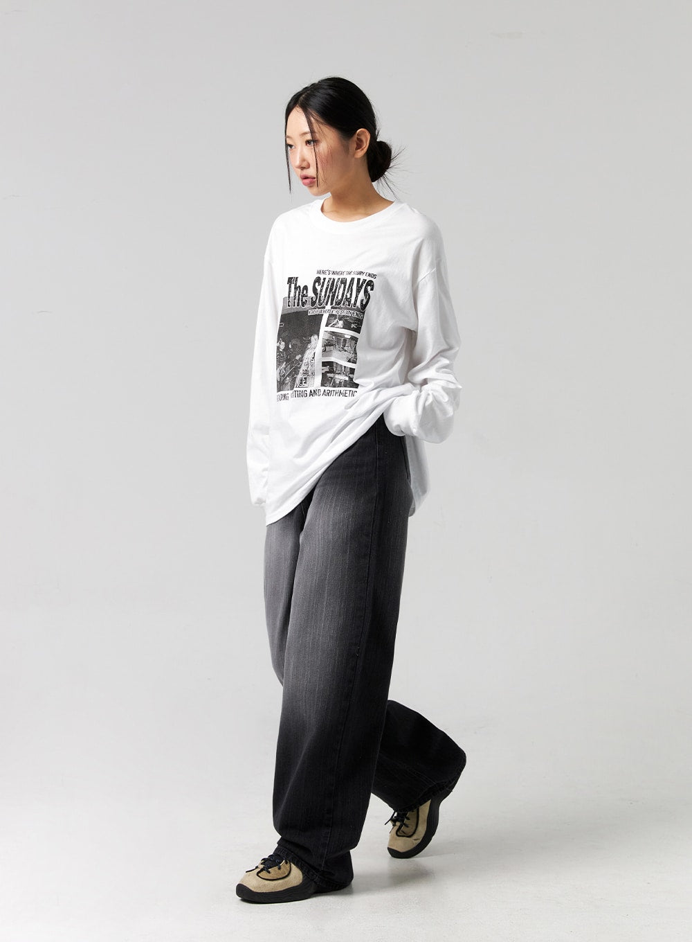 Washed Wide-Leg Jeans CG327 in black, full-body side shot on model with crossed legs, wide-leg washed cotton denim showing leg drape and length, paired with oversized graphic tee and chunky sneakers.