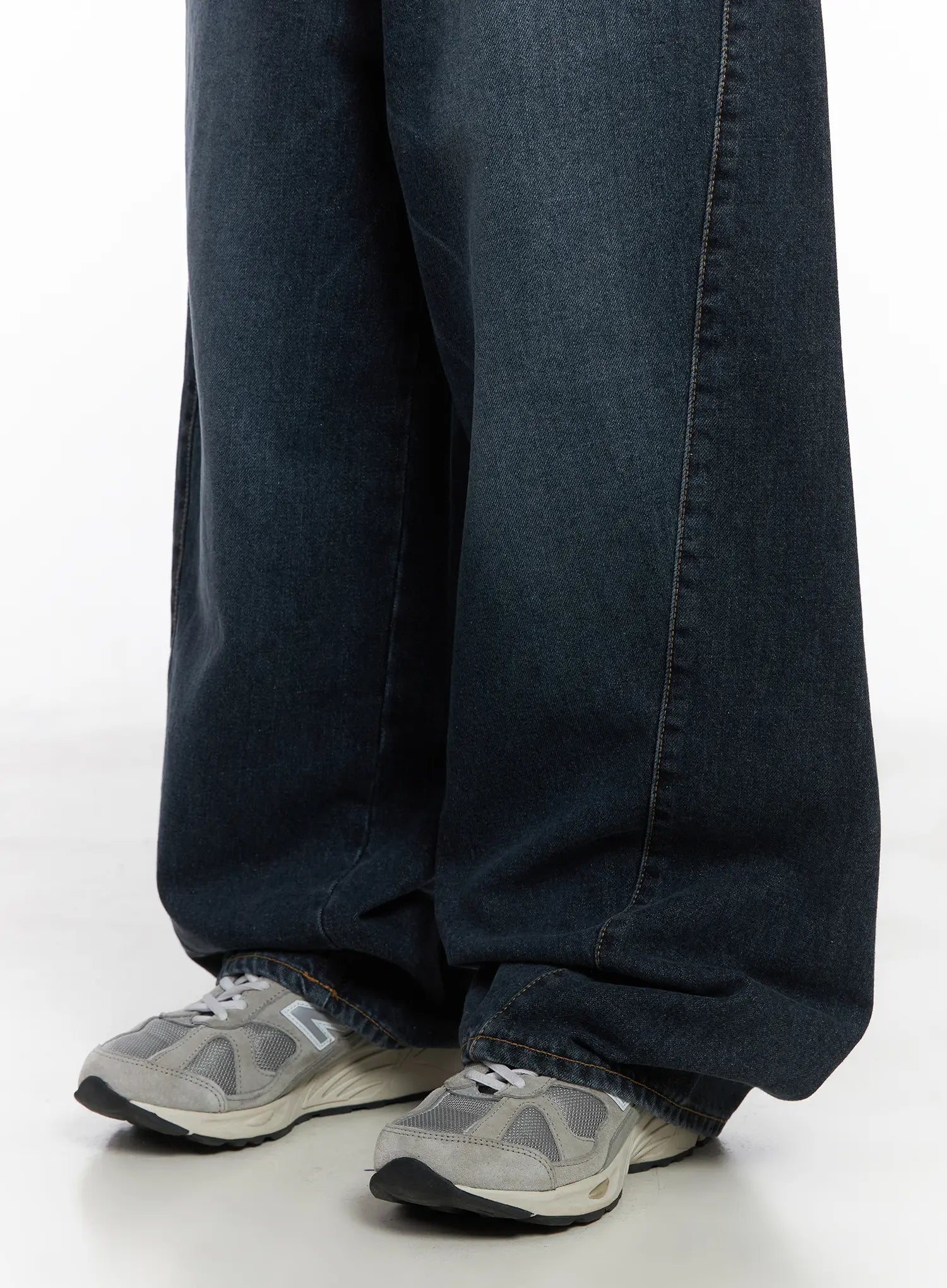 Everly Wide Leg Jeans CJ513 in dark blue, lower-leg detail close-up on model, extra-wide hem pooling over grey sneakers, washed cotton fabric with center seam detail visible.