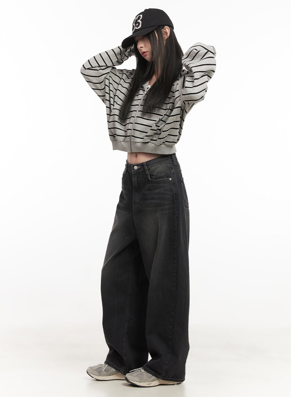 Ruth Washed Wide-Leg Jeans CF514 in black, side full-length view on model with arms raised, oversized wide-leg drape visible, paired with grey striped crop hoodie and cap.