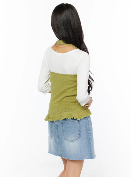 Frill Hem Halter Neck Top CU522 in green, back view on model, showing halter neck strap, pointelle knit back panel, and frill hem, layered over white long-sleeve top with denim mini skirt.