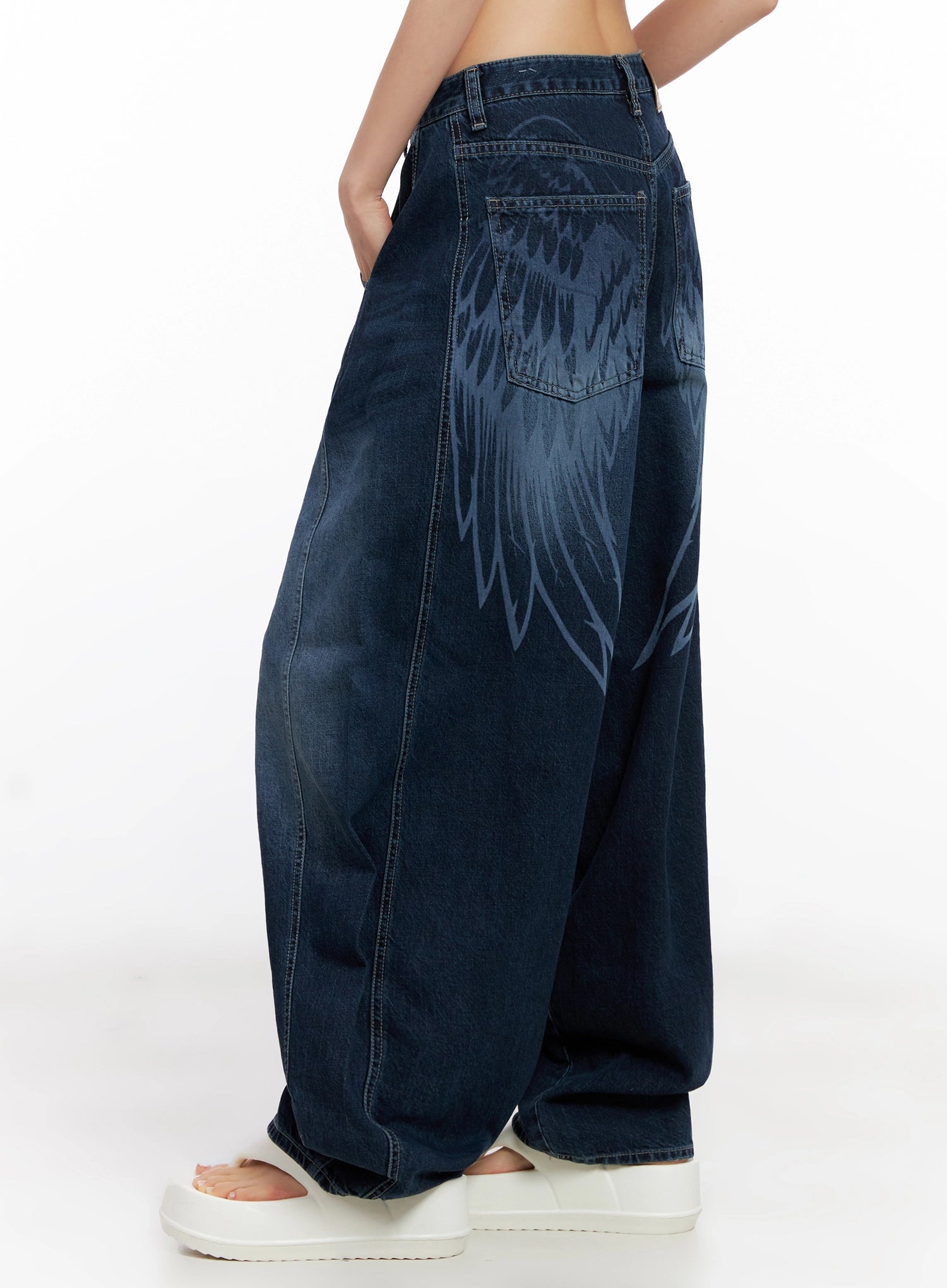 Sohee Angel Wing Print Wide-Leg Jeans IG508 in dark blue, back three-quarter close-up on model, bold angel wing graphic print spanning hip and thigh, washed cotton wide-leg denim.