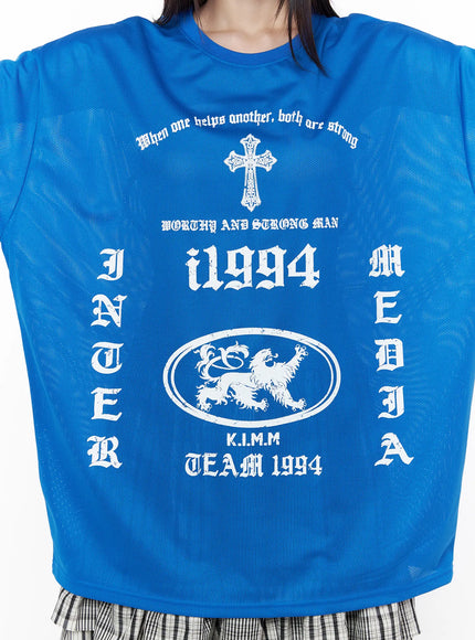 Oversized Mesh Graphic Tee CU519 in Blue M/L, front graphic close-up on model, mesh fabric texture visible, full white gothic INTER MEDIA cross i1994 lion crest TEAM 1994 print layout detail.