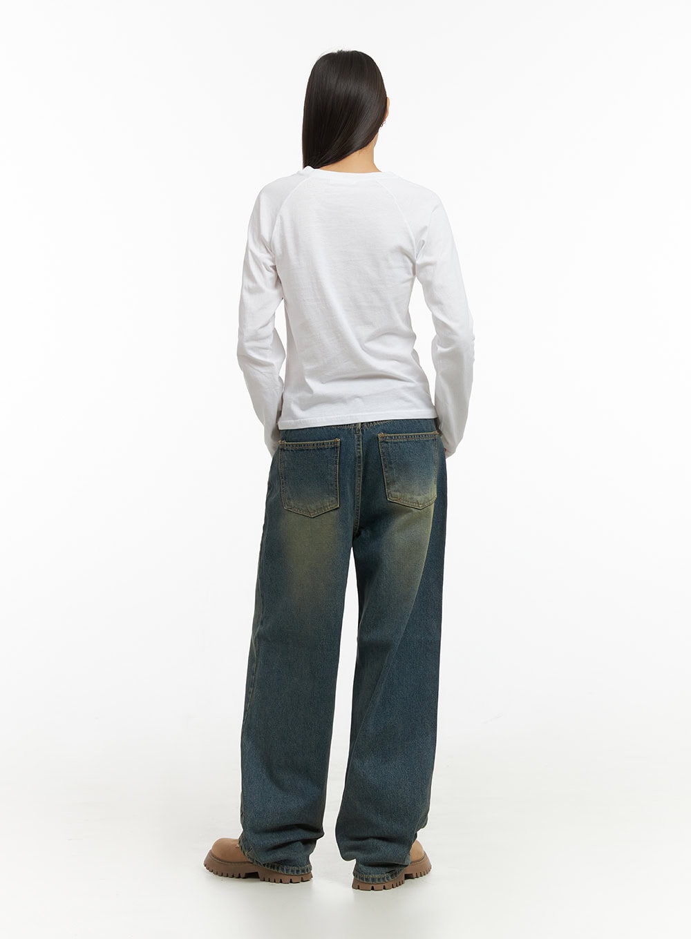 Anya Wide Fit Denim Jeans IO409 in blue, back view on female model standing, wide-leg washed denim with dual back pockets and green-yellow tinted fade, styled with plain white long-sleeve top.