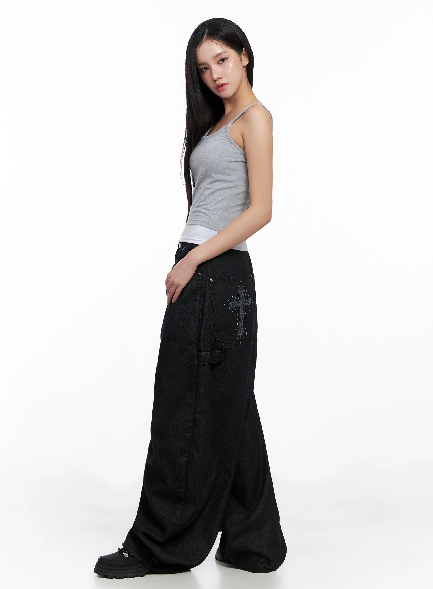 Lea Cross-Patch Baggy Jeans IS525 in black, side view on model, leopard-print cross patchwork with stud details visible on back pocket, extreme wide-leg cotton denim silhouette, styled with grey cami top.