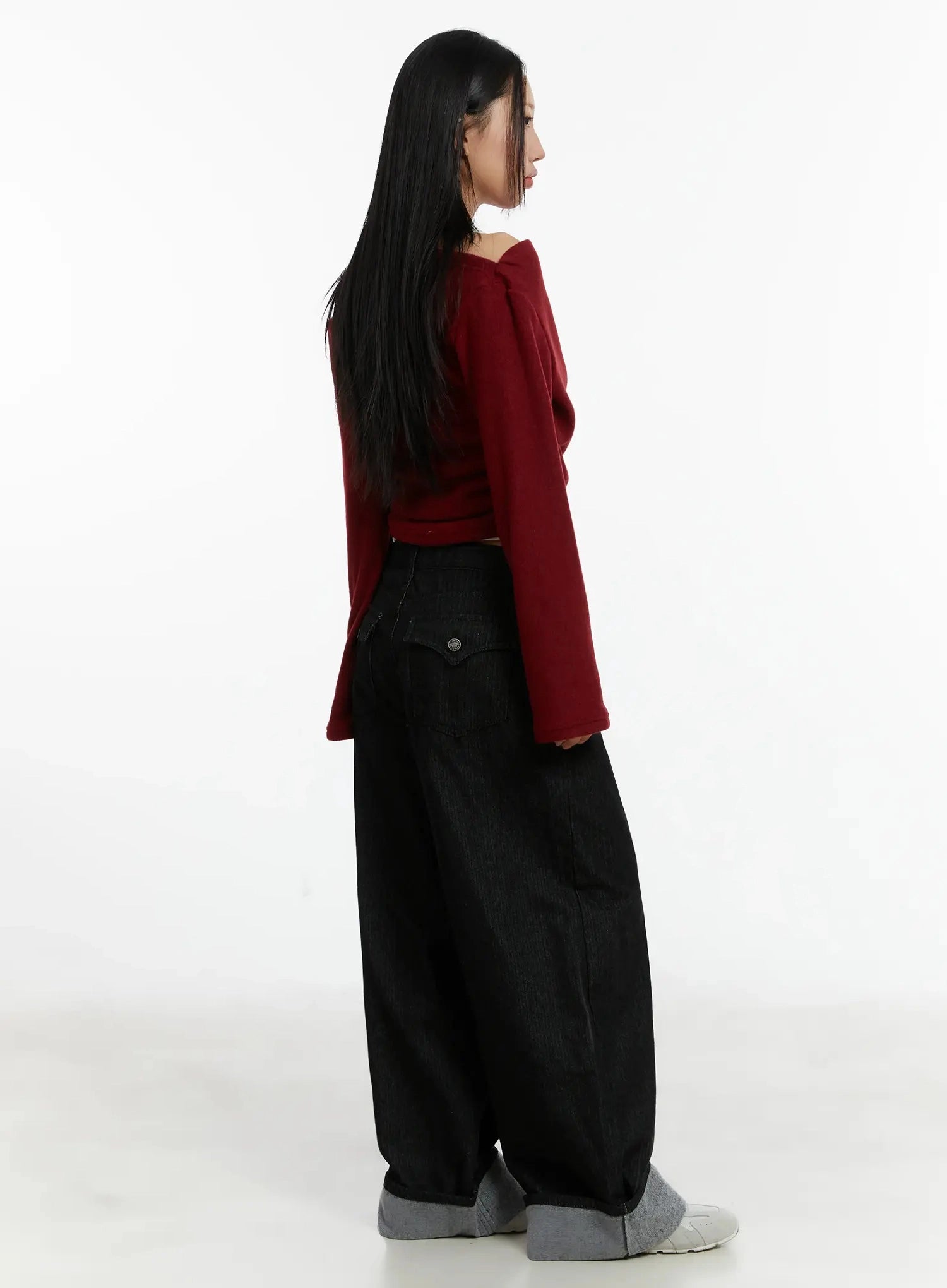 Amyra Baggy Striped Jeans ID525 in black, side view on model, wide-leg baggy silhouette with back pocket detail visible, paired with red off-shoulder crop knit, grey cuffed hem.