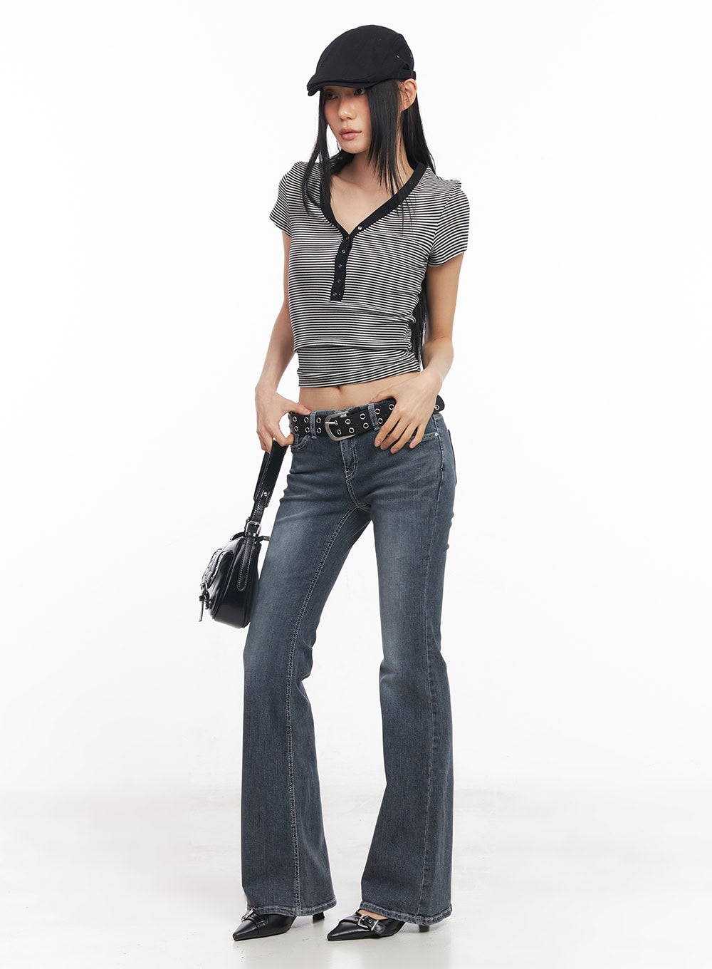 Nadeline Slim Bootcut Jeans CY528 in dark gray, full-body three-quarter front shot on model with cap and grommet belt, slim bootcut washed denim styled with striped crop top and black saddle bag.