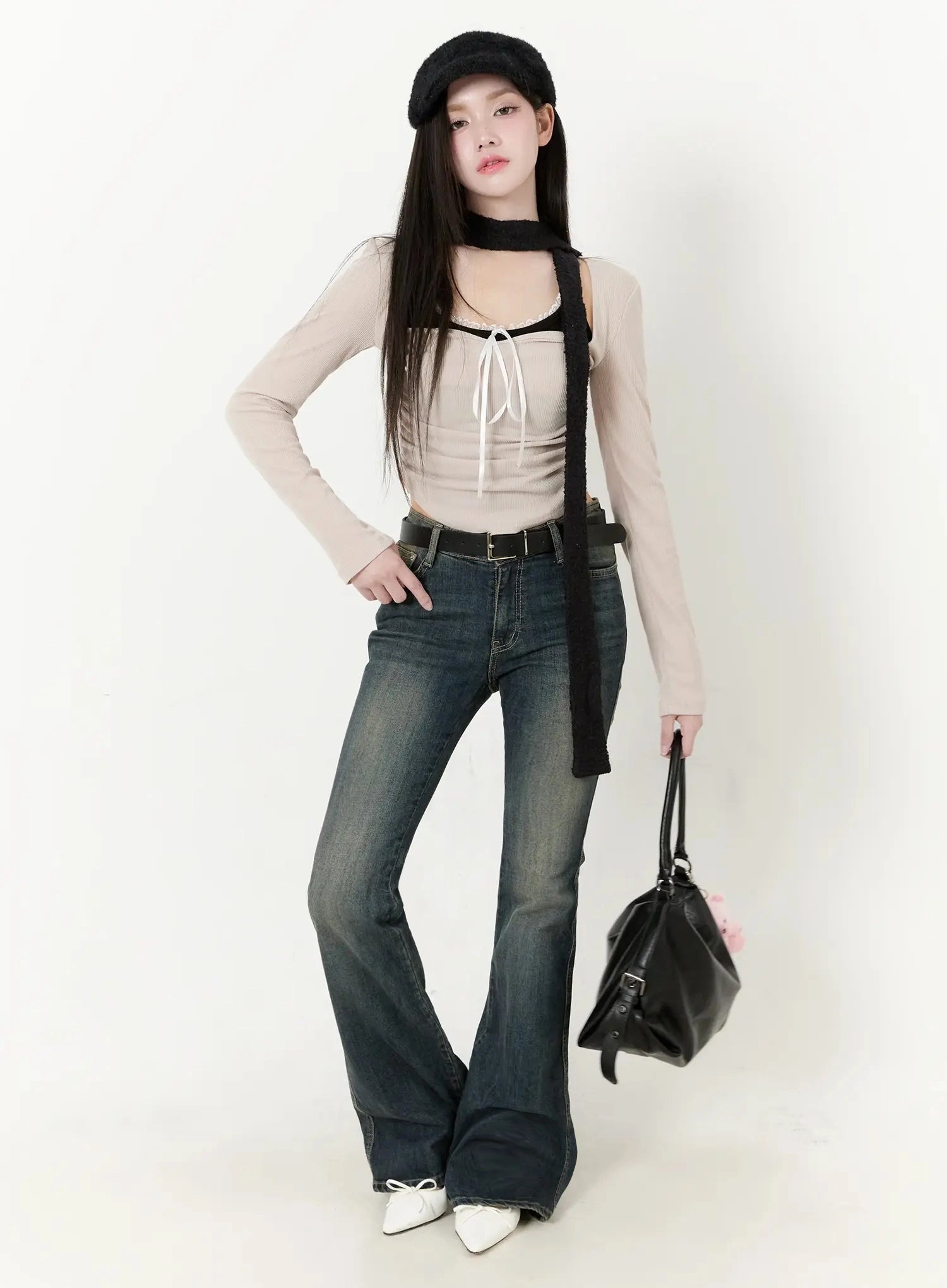 Karla Vintage Logo Hip Pad Flare Jeans IO520 in washed dark blue, front full-body on model with hand on hip, slim waist and wide flare hem, paired with beige top and black beret.