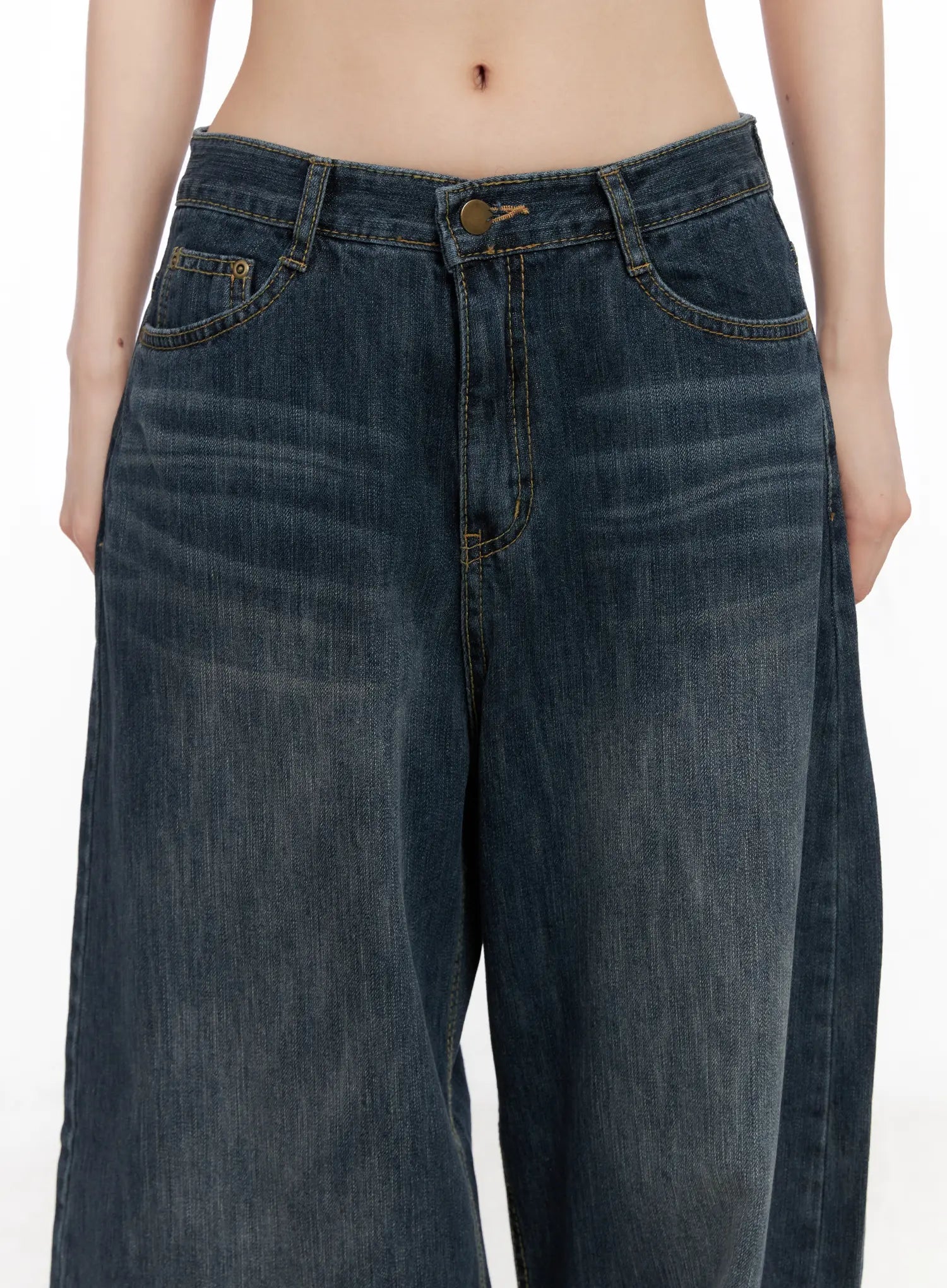 Seoy Washed Denim Jeans CG525 in dark blue, close-up waist detail on model, bronze button, contrast yellow stitching, front pockets, and washed denim texture.