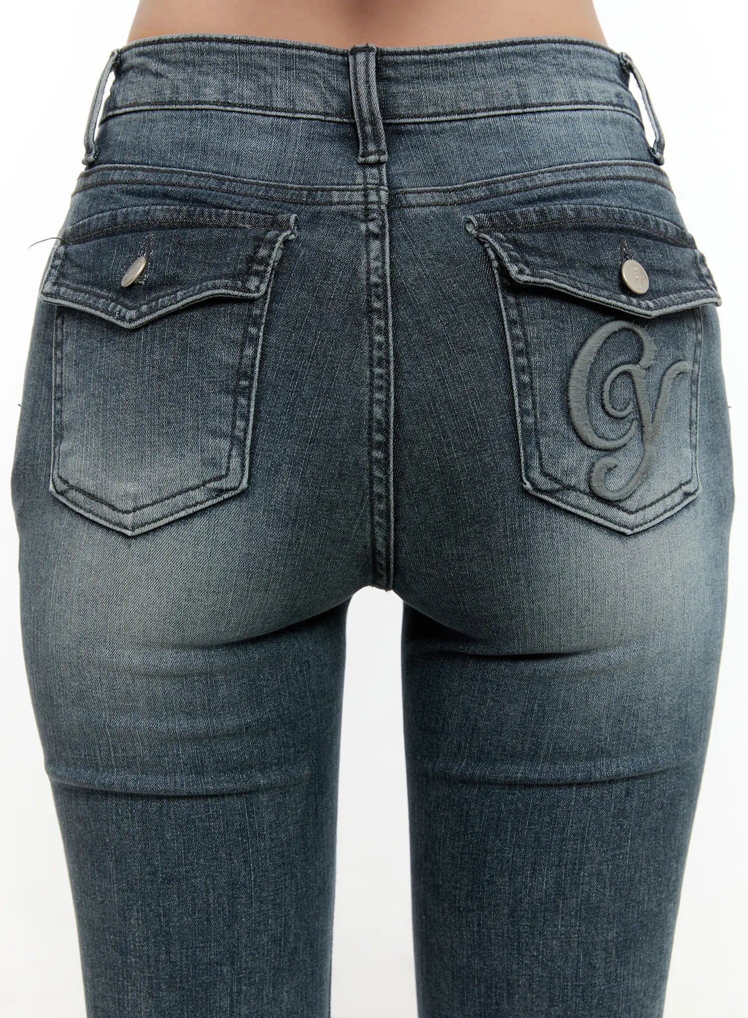 Marley Hip-Pad Denim Bootcut Jeans CN506 in dark blue, macro back close-up on model, dual snap-button hip-pad pockets and tonal embroidered logo detail on right pocket, washed denim texture visible.
