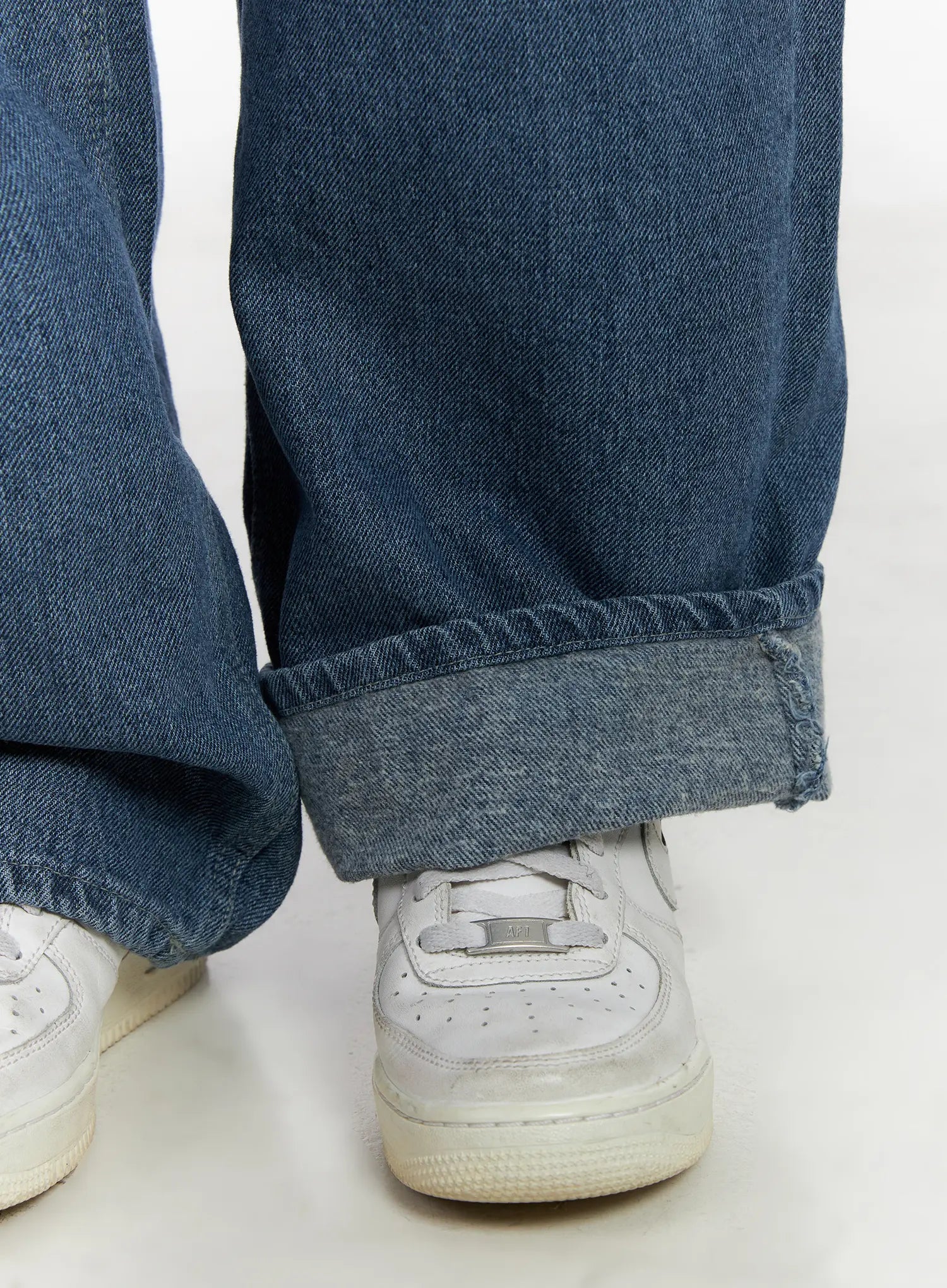 Mariam Baggy Jeans CN526 in blue, close-up hem detail, wide cotton denim leg pooling over white sneakers, washed indigo fabric texture visible at cuff.