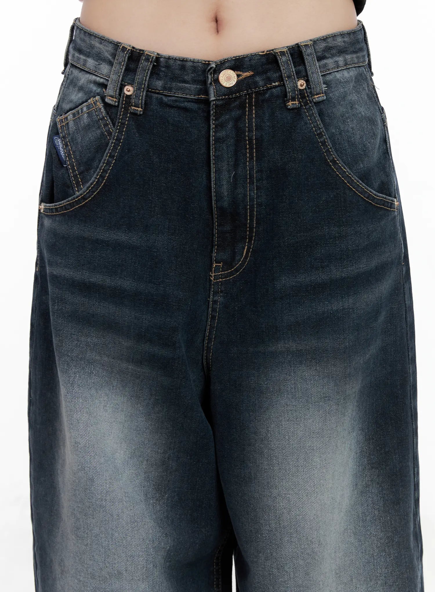 Isla Washed Baggy Jeans CO521 in dark blue, front waistband close-up on model, gold button closure, contrast stitching, coin pocket, and washed denim texture clearly visible.