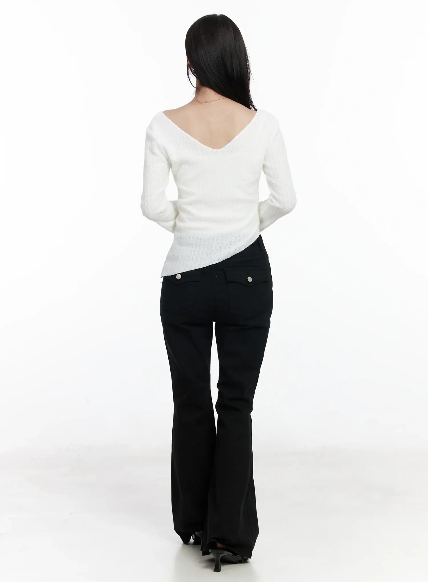 Ellis High-Waist Bootcut Jeans IJ529 in black, back full-body shot on model, bootcut hem sweeping the floor, back flap pockets visible, paired with white V-back knit top and heels.