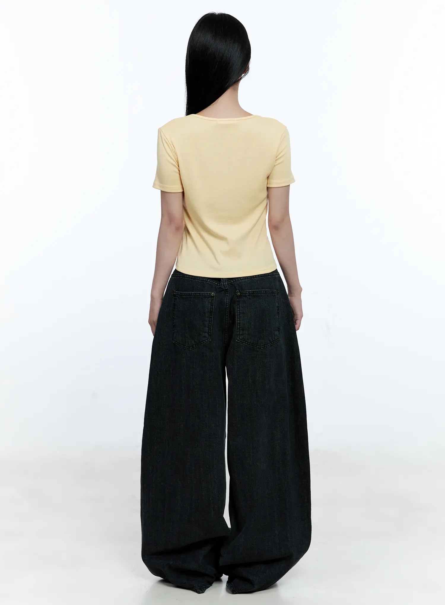 Wynter Star Embroidered Denim Jeans CG507 in black, full-body back view on model, oversized wide-leg silhouette, dual back patch pockets, paired with yellow crop top, floor-length hem.