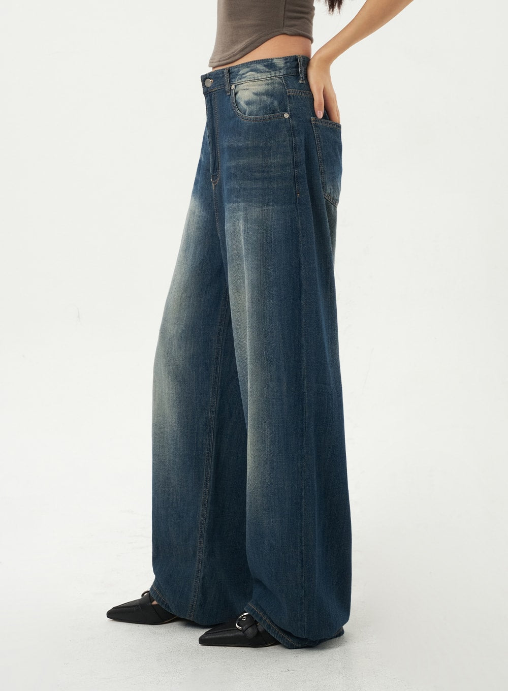 Baggy Low Rise Jeans CA326 in dark blue, side profile mid-shot on model hand in pocket, baggy wide-leg cotton denim with heavy fading along outer seam, low waistband.