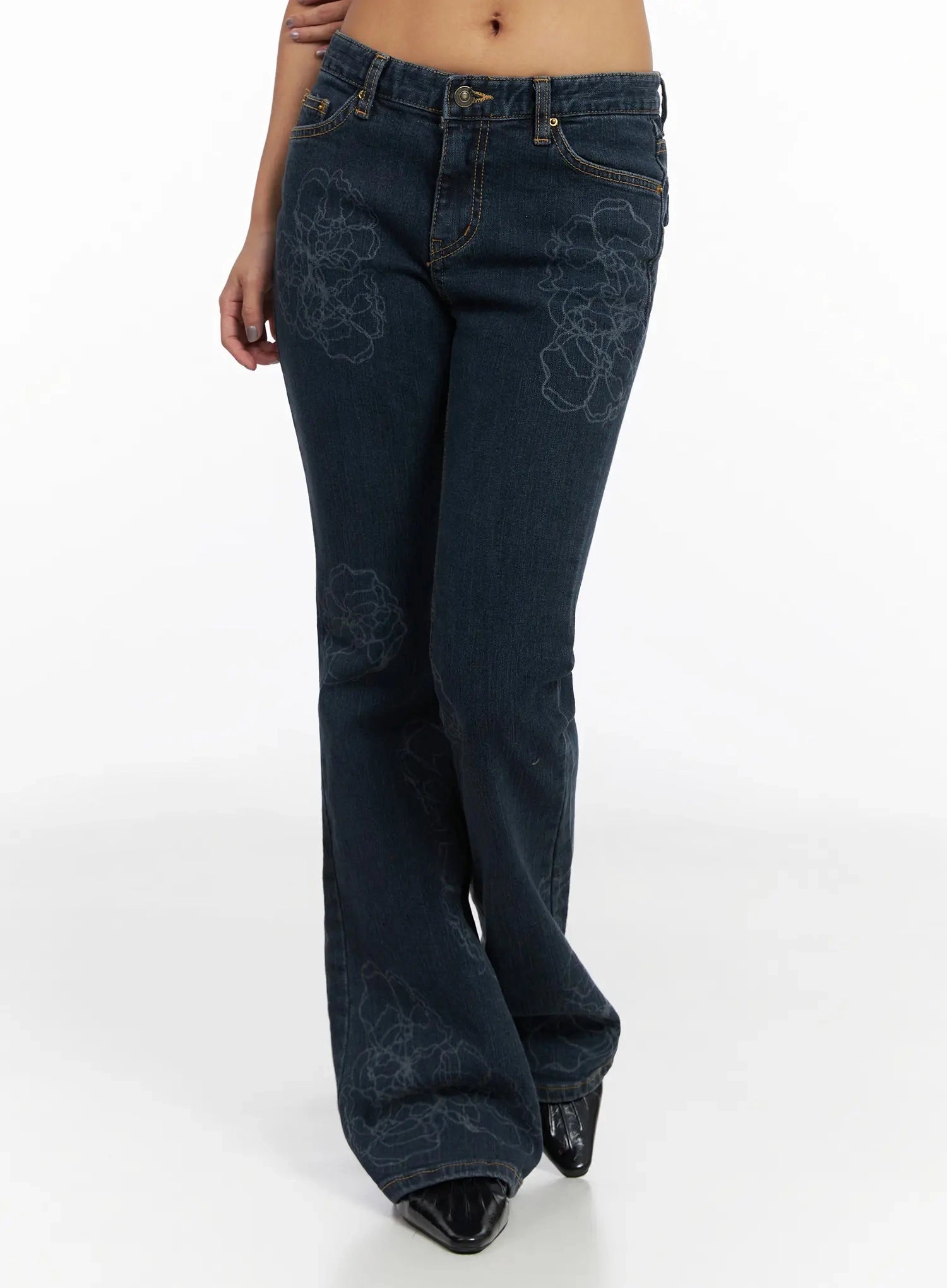 Amari Floral Embriodered Bootcut Jeans IN528 in dark blue, front three-quarter product shot waist to hem on model, floral outline embroidery covering thigh and lower leg, bootcut flare, black patent boots.