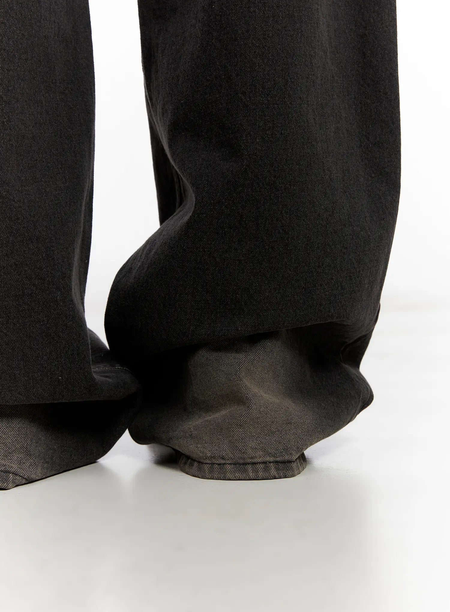 Ari Washed Wide-Leg Denim Jeans CL521 in Black, hem detail close-up, extra-long wide cotton leg pooling heavily on floor, showing raw frayed hem edge and voluminous silhouette.