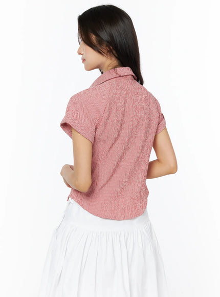 Gingham Button-Up Short Sleeve Blouse CU522 in red, back view on model, showing cropped back hem, cuffed sleeves and seersucker gingham texture, paired with white skirt.