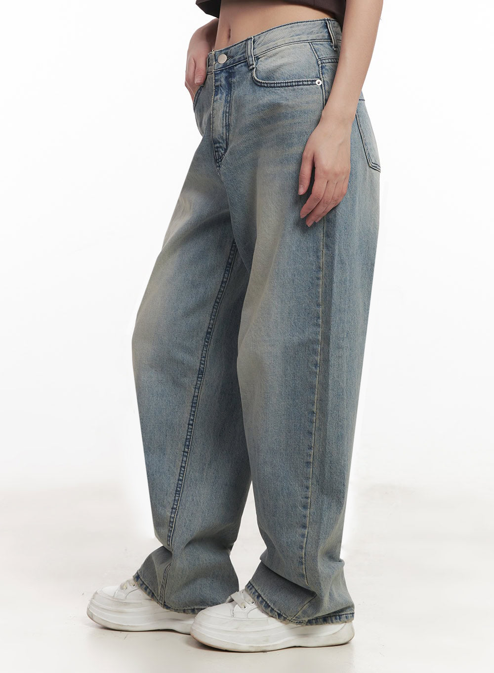 Casey Washed Baggy Jeans IM528 in light blue, side close-up from waist to ankle on model, washed cotton denim with curved wide leg, front coin pocket and side seam detail, stacked at hem over white sneakers.