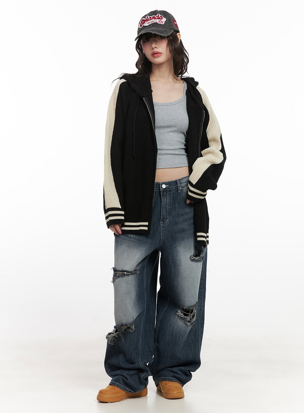 Alison Destroyed Baggy Jeans CJ523 in dark blue, full-body front shot on model styled with black varsity knit cardigan and graphic cap, grunge street look with frayed rip details.