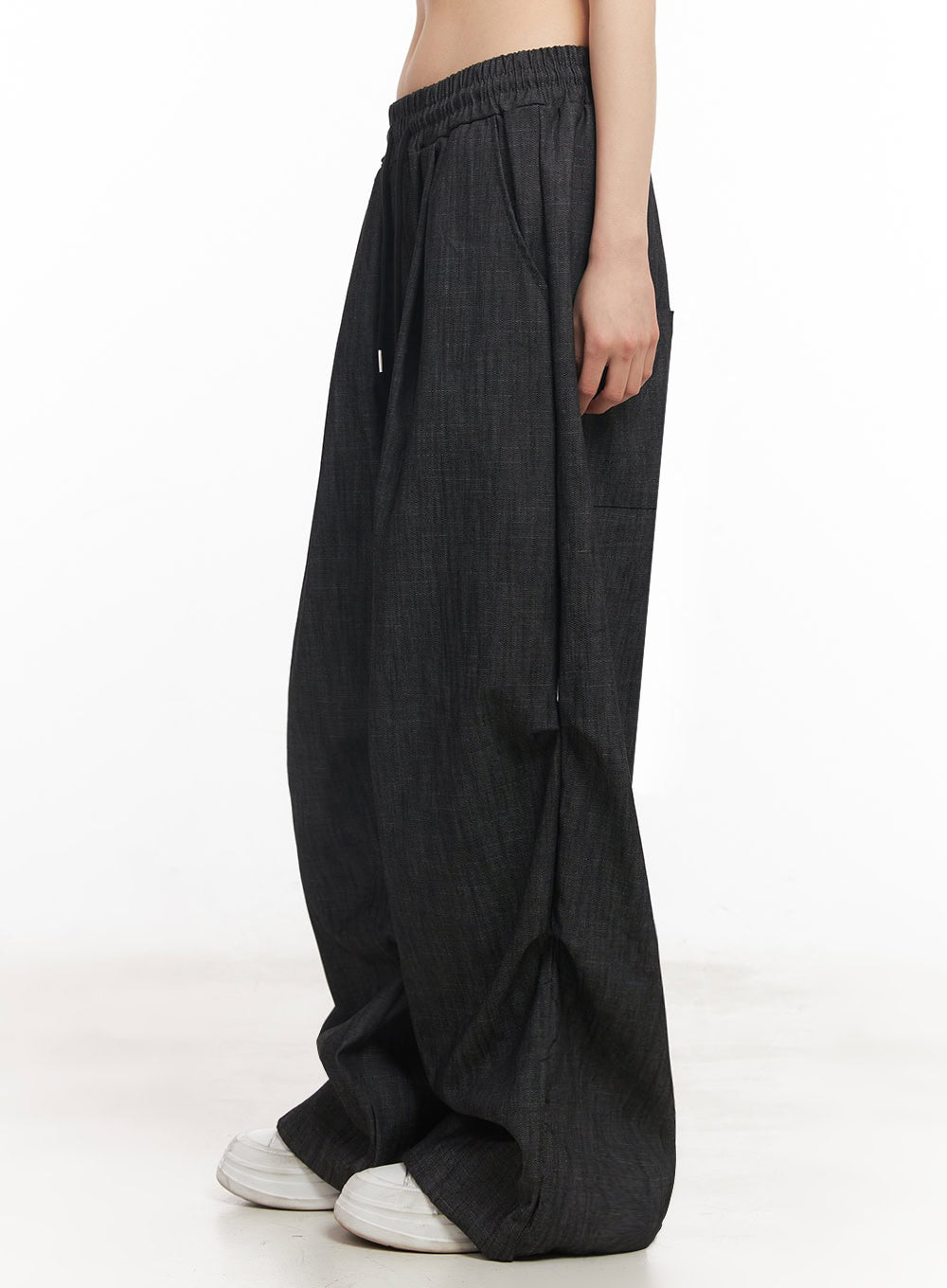 Pintuck Denim Sweatpants IY529 in black, side close-up on model, elastic waist with drawstring, pintuck crease, side patch pocket, wide-fit denim leg in lightweight cotton fabric.