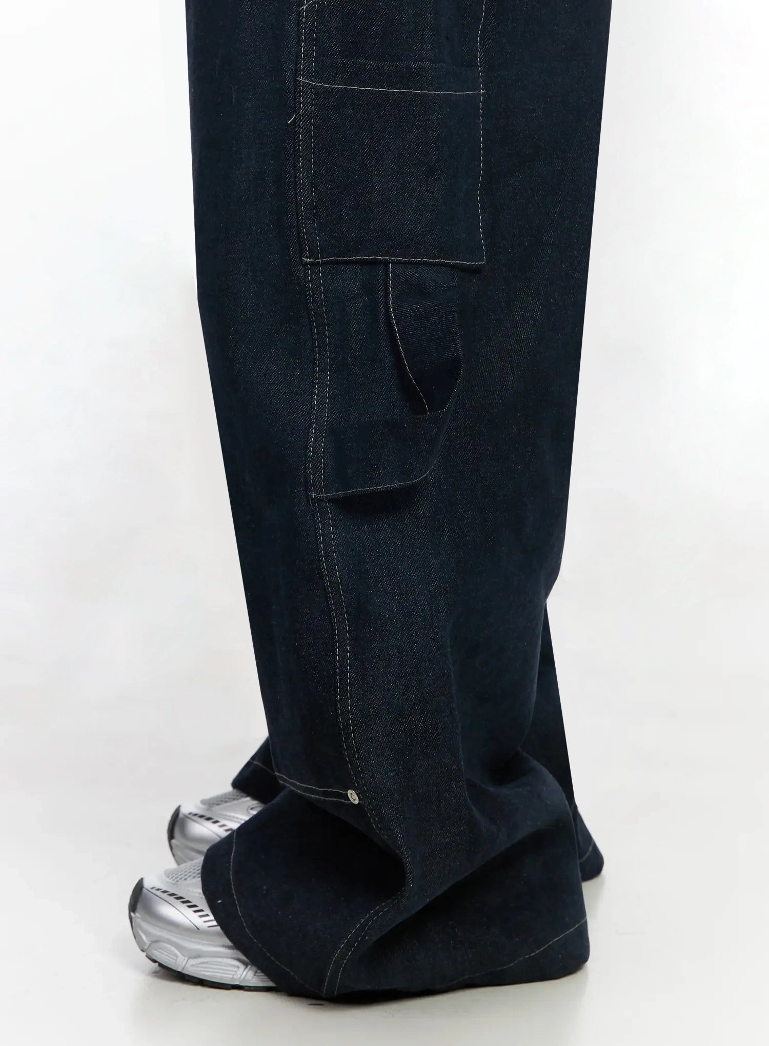 Ashlyn Carpenter Wide-Leg Jeans IJ528 in dark blue, close-up side detail of thigh-to-hem area, open carpenter side pocket with contrast topstitching and rivet, wide flared hem on sneakers.