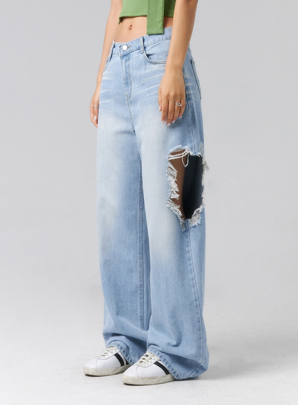 Ripped Side Jeans CL320 in light blue, front side close-up on model, highlighting large open destroyed rip at outer thigh with heavily frayed edges, wide-leg cotton denim, white sneakers.