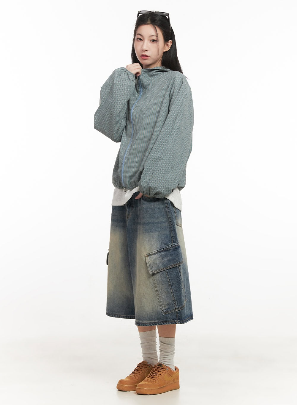 Cargo Bermuda Denim Shorts CF514 in dark blue, three-quarter side editorial shot on model, wide-fit washed denim with cargo pocket, layered under sage hooded jacket, tan sneakers.