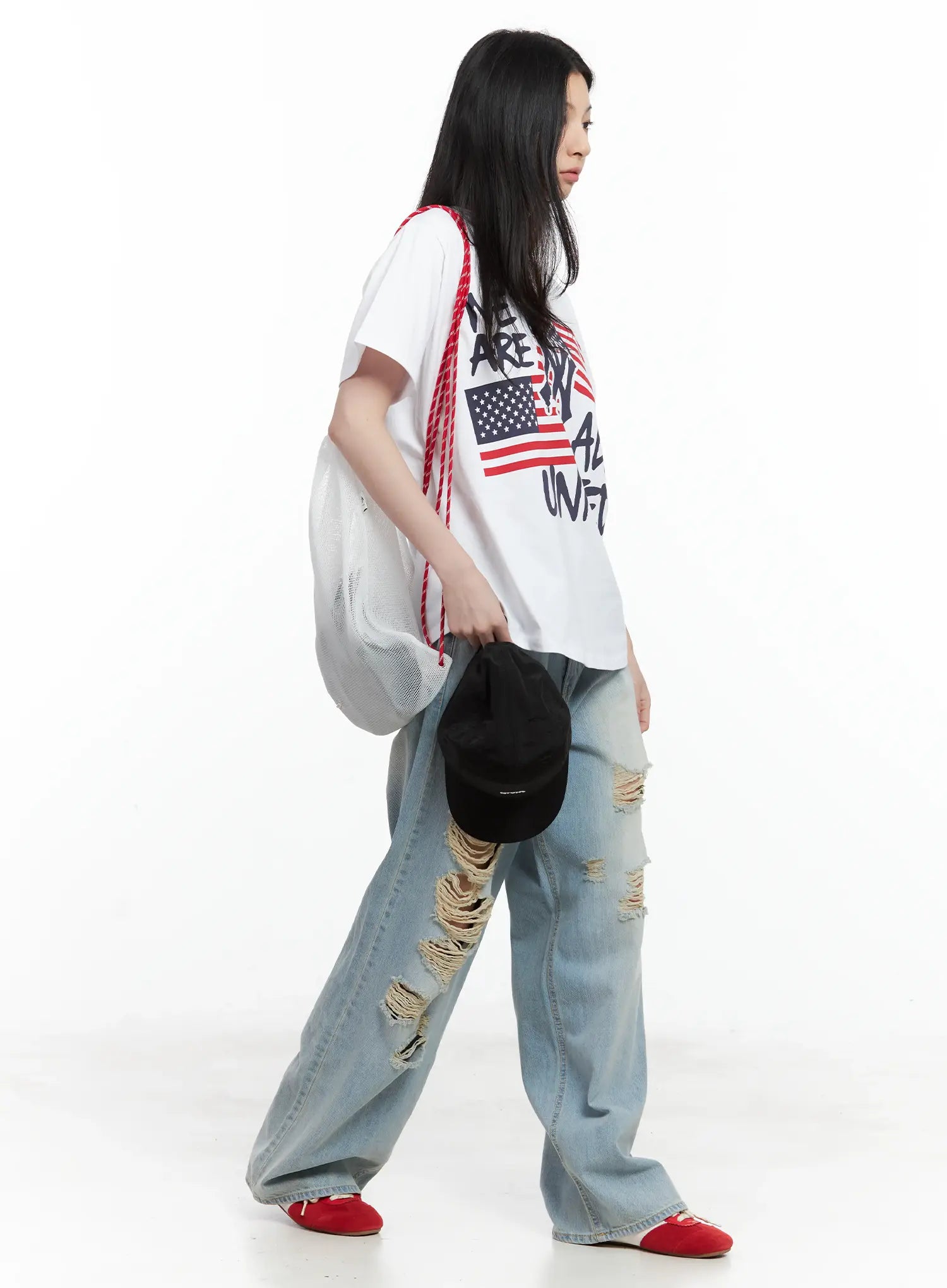 Gyuri Dirty-Wash Distressed Wide Jeans CU530 in blue, side walking shot on model, graphic tee with mesh tote bag, frayed rip detail in motion, wide-leg silhouette, red flats.