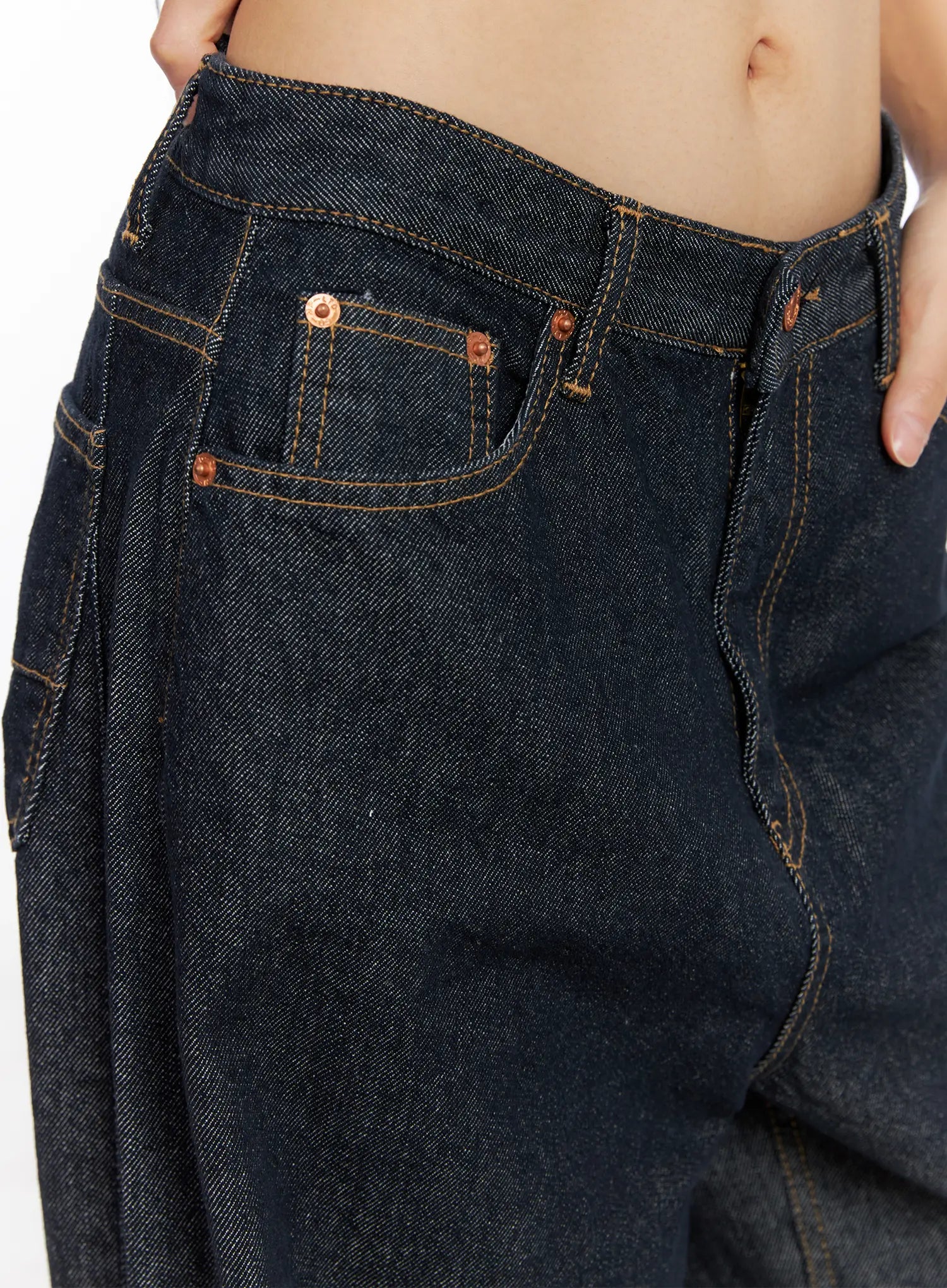 Oakley Cuffed Wide-Leg Jeans CS511 in dark blue, waistband close-up on model, five-pocket construction with copper rivets, contrast topstitching, coin pocket, and low-rise waistband detail.