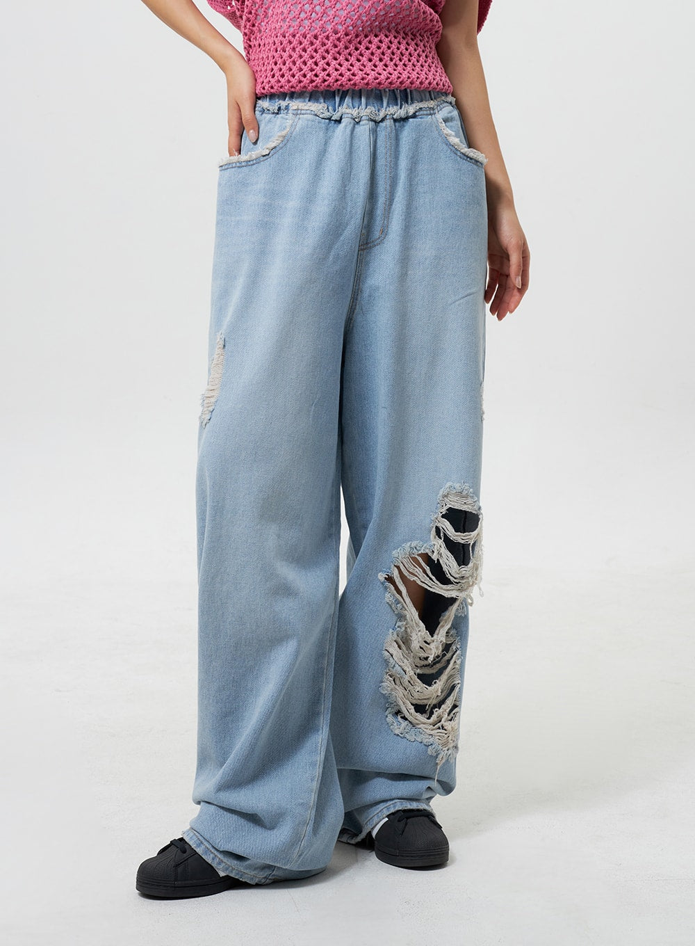 Oversized Ripped Jeans CY324 in light blue, front close-up on model, highlighting large destroyed rip with exposed frayed threads, frayed pocket trim, and elastic banded waist.