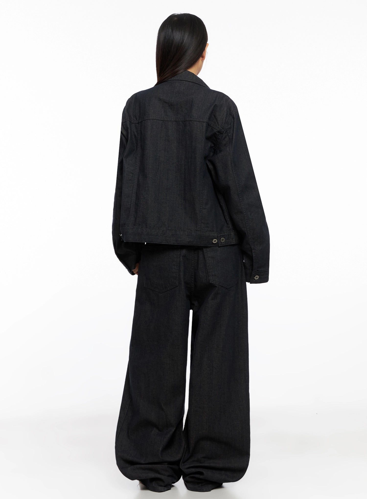 Heidi Wide-Leg Jeans IG527 in dark blue, back full-body on model, showing rear patch pockets, wide pooling hem, paired with dark denim jacket and brown leather belt.
