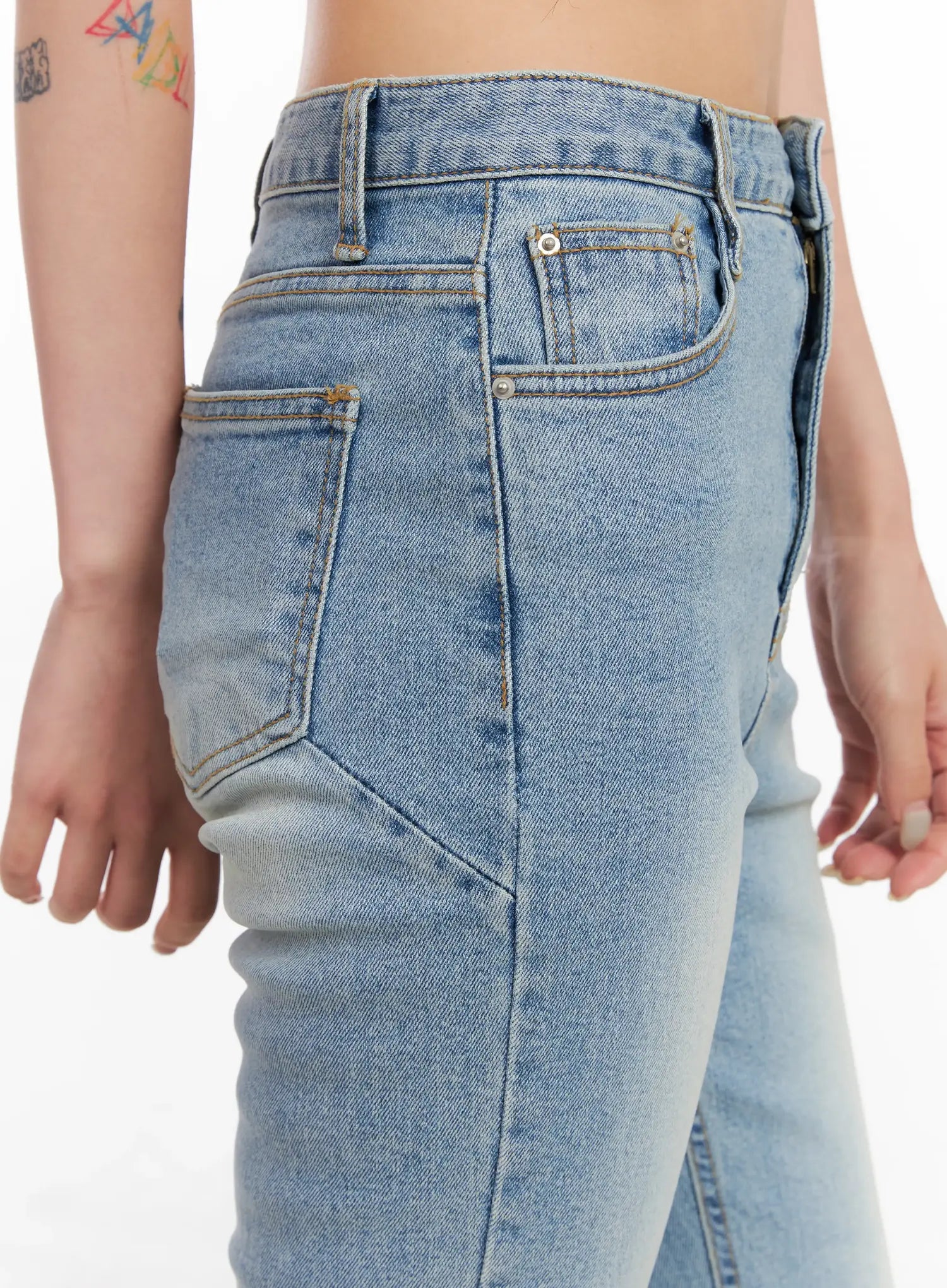 Byeol Washed Flare Denim Jeans CL525 in light blue, close-up of rear hip and back pocket on model, gold rivet hardware, contrast stitching, and angled seam detail.
