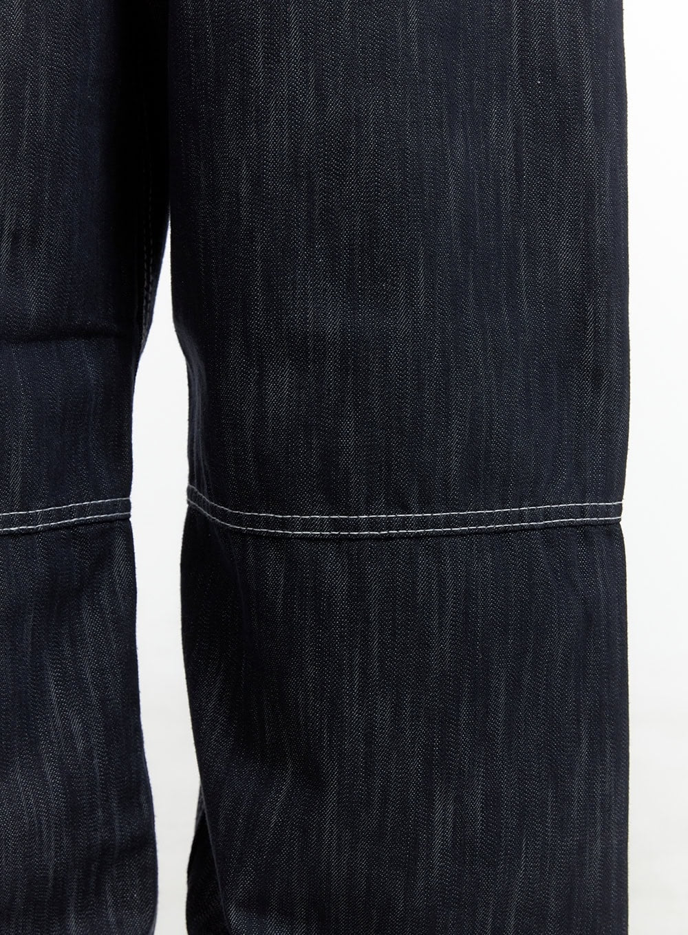 Low-Rise Strap Baggy Jeans CY414 in dark blue, detail close-up of lower leg panel seam with white contrast stitch on dark denim, showing fabric texture and panel construction.