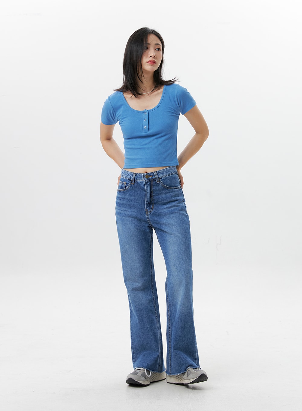 Straight-Leg Jeans OG318 in medium blue, front full-length on model, hands behind back pose, high-rise 5-pocket straight-leg denim, slight bootcut silhouette, raw hem, blue ribbed crop top.