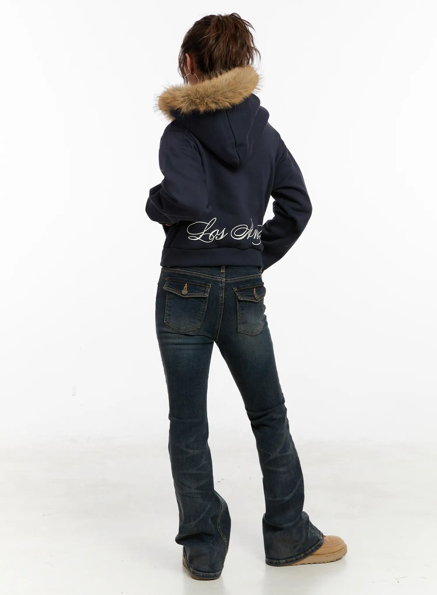 Kai Vintage Washed Flare Jeans CD515 in dark indigo, back three-quarter view on model, showing flare leg and back pocket detail, styled with navy script-print hoodie and UGG boots.