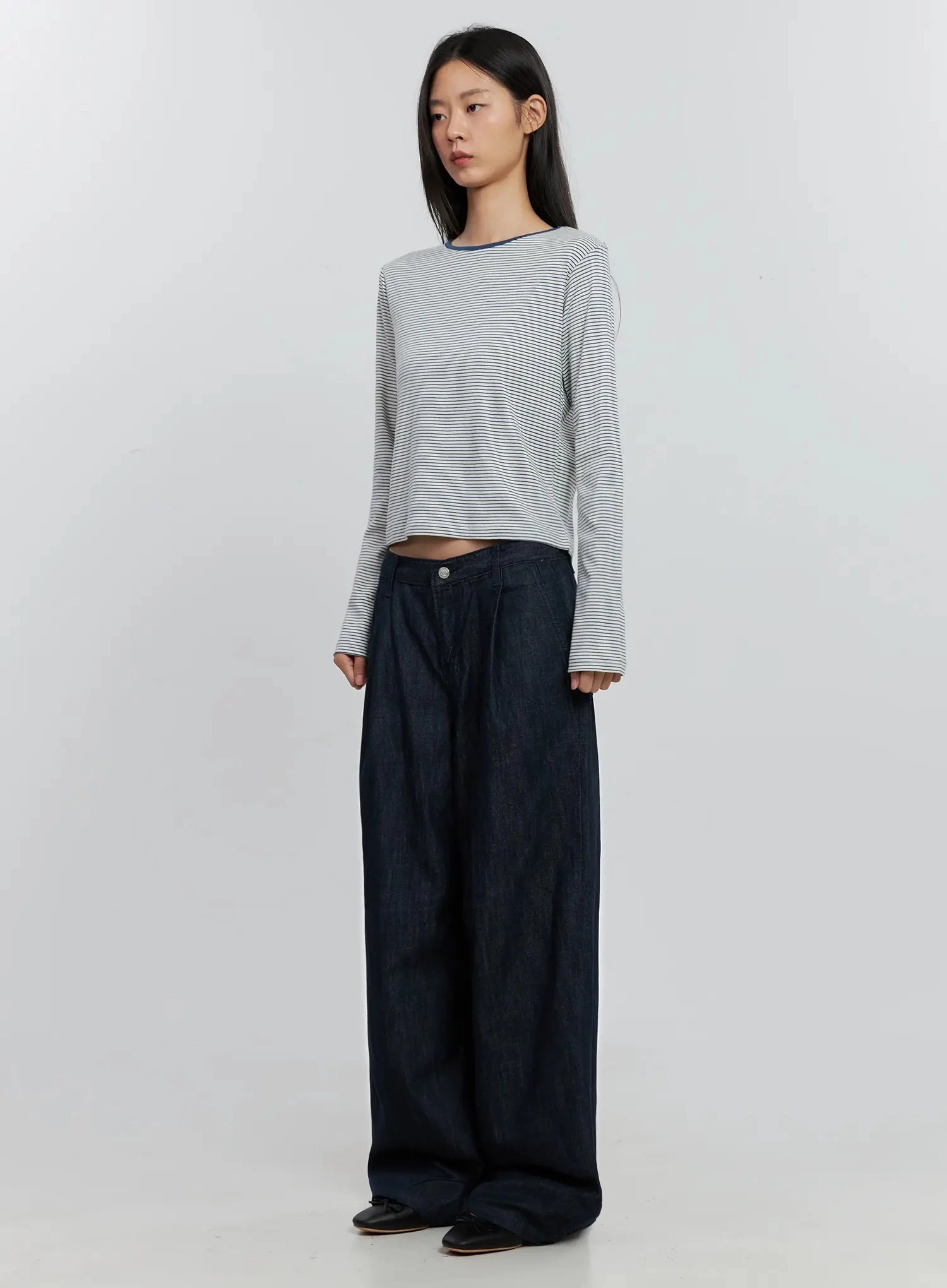 Elio Pintuck Wide-Leg Jeans IS516 in dark indigo, three-quarter front angle on model, low-rise pintuck jeans with voluminous leg, paired with white striped crop top.