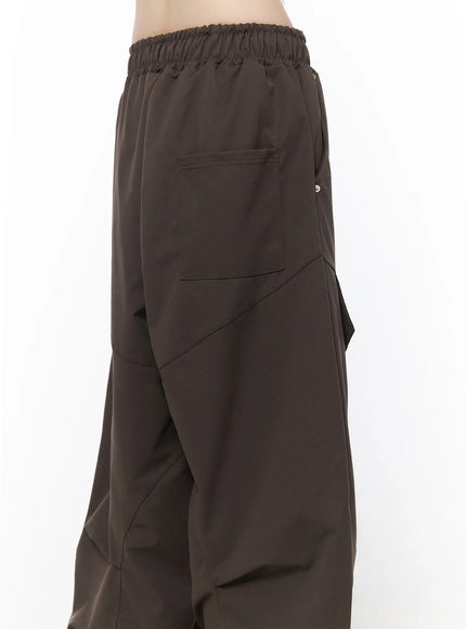 Wide Leg Pintuck Cargo Pants CU519 in dark brown, rear upper-leg close-up on model, back patch pocket, diagonal pintuck seam lines, and ruched elastic waistband visible.