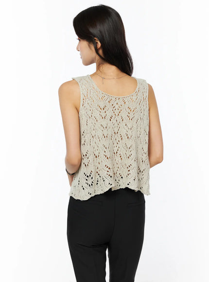 Crochet Knit Sleeveless Top CU522 in beige, back view on model, open-knit lace pattern across back, scoop back neckline and relaxed cropped fit, styled with black trousers.