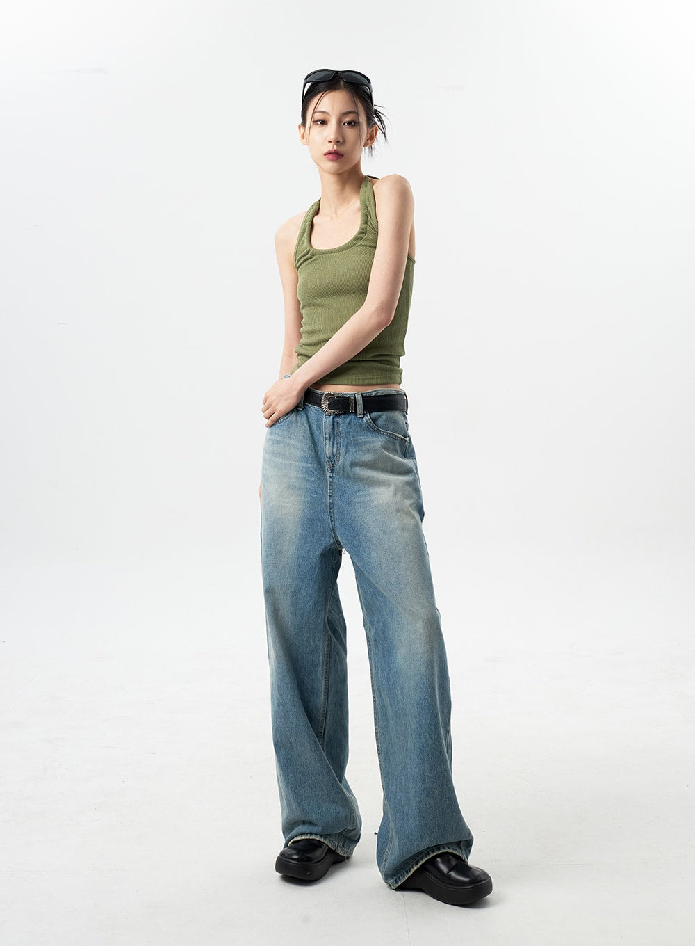 Oversized Jeans Unisex CY312 in washed blue, full-length three-quarter front view on model, wide-leg relaxed denim with sun-faded wash, green halter top and black belt.